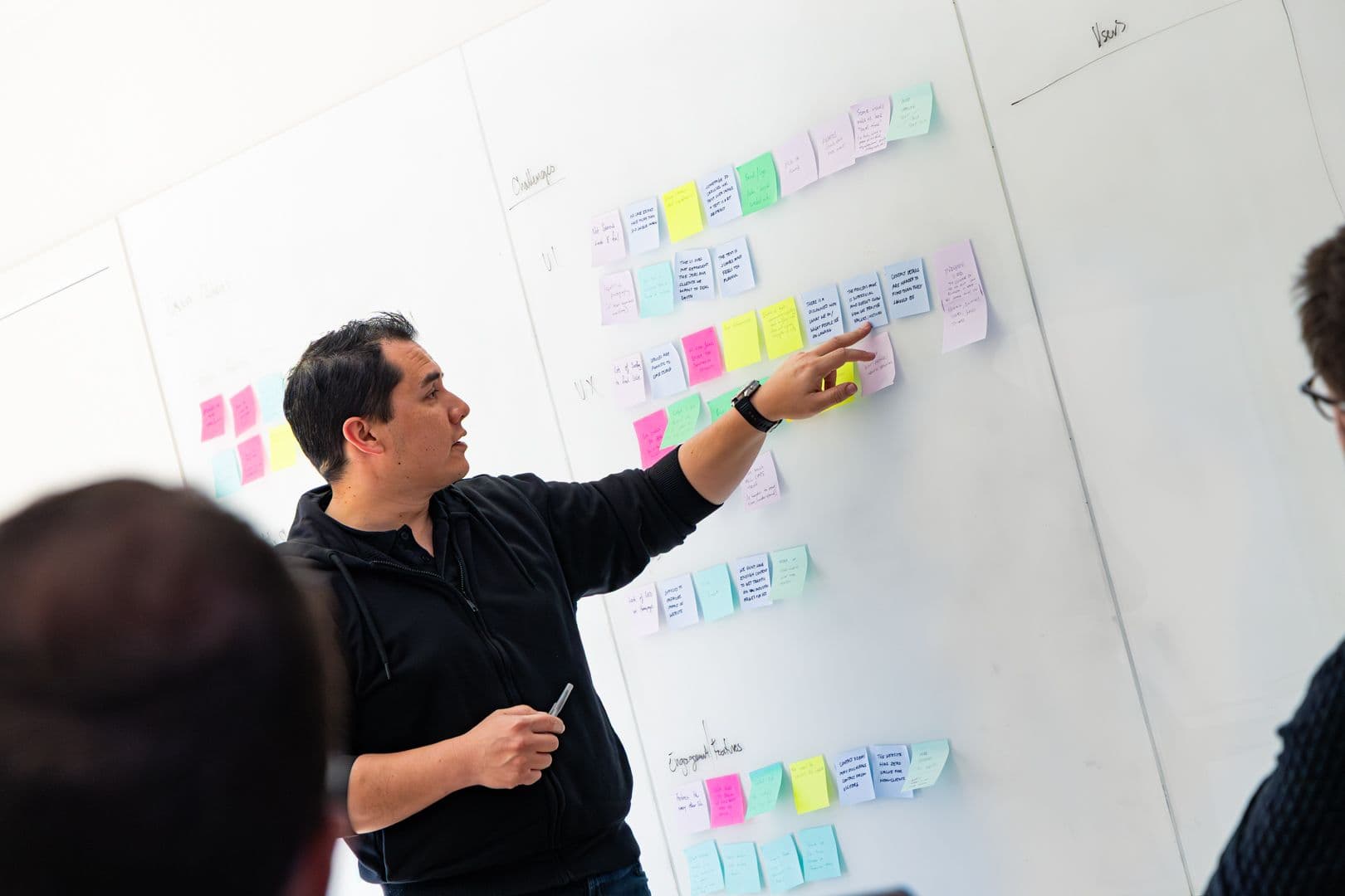 A team member pointing at a wall of coloured sticky notes during a workshop