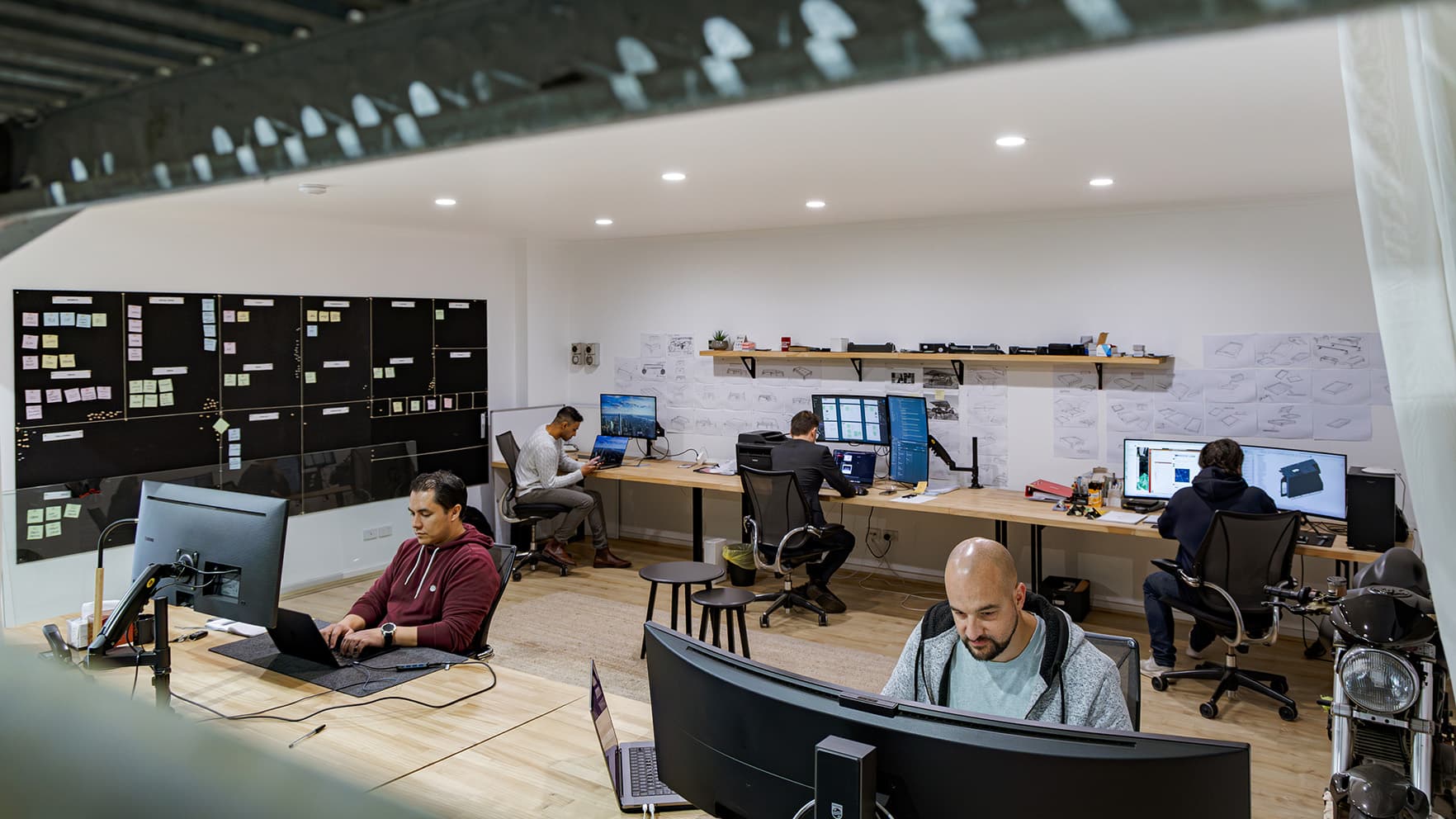 The CodeFish Studio floor in Adelaide, developers at desks with a project planning wall behind them
