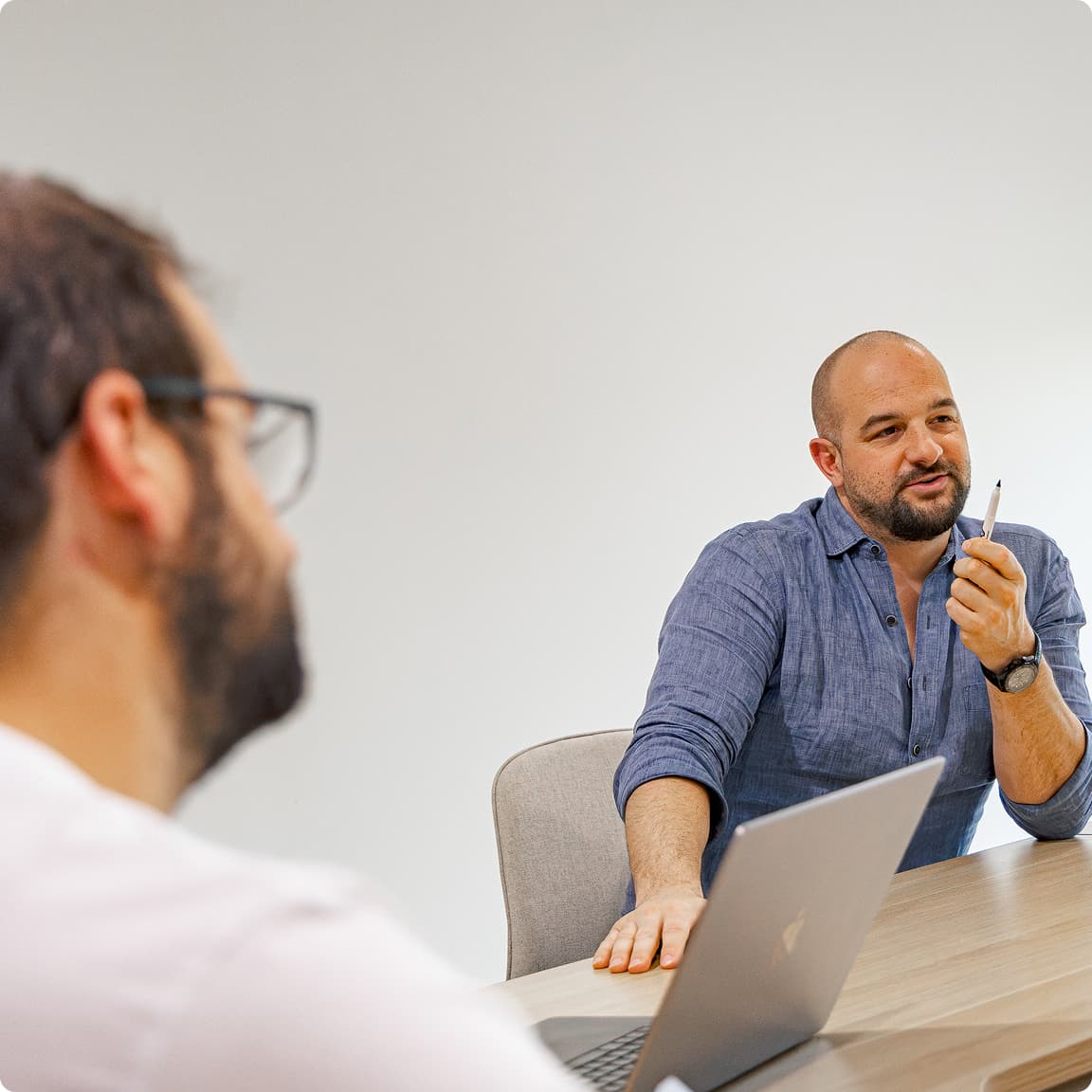 Two CodeFish team members in discussion across a meeting room table, one taking notes