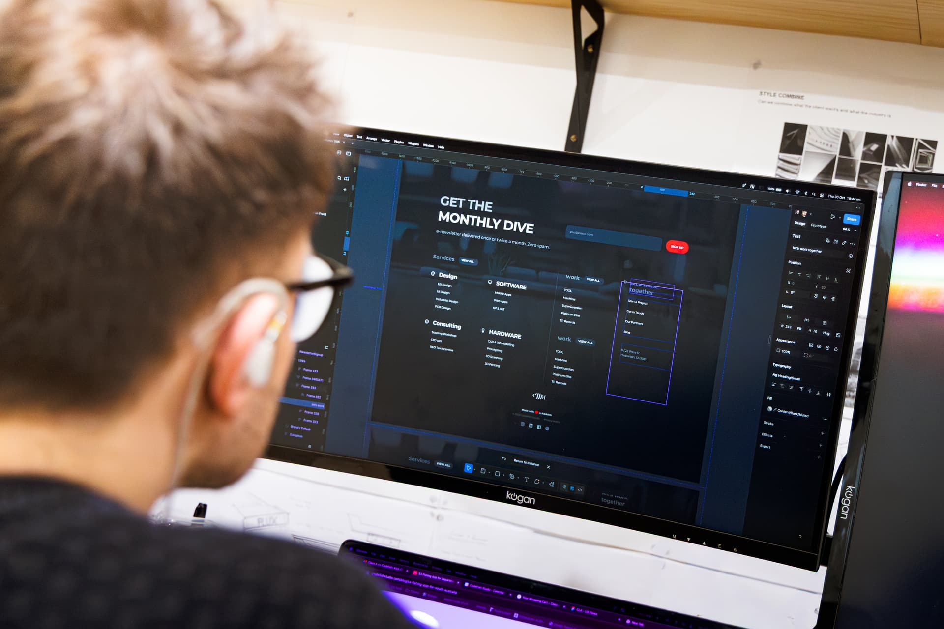 A designer reviewing a website layout in Figma on a large monitor